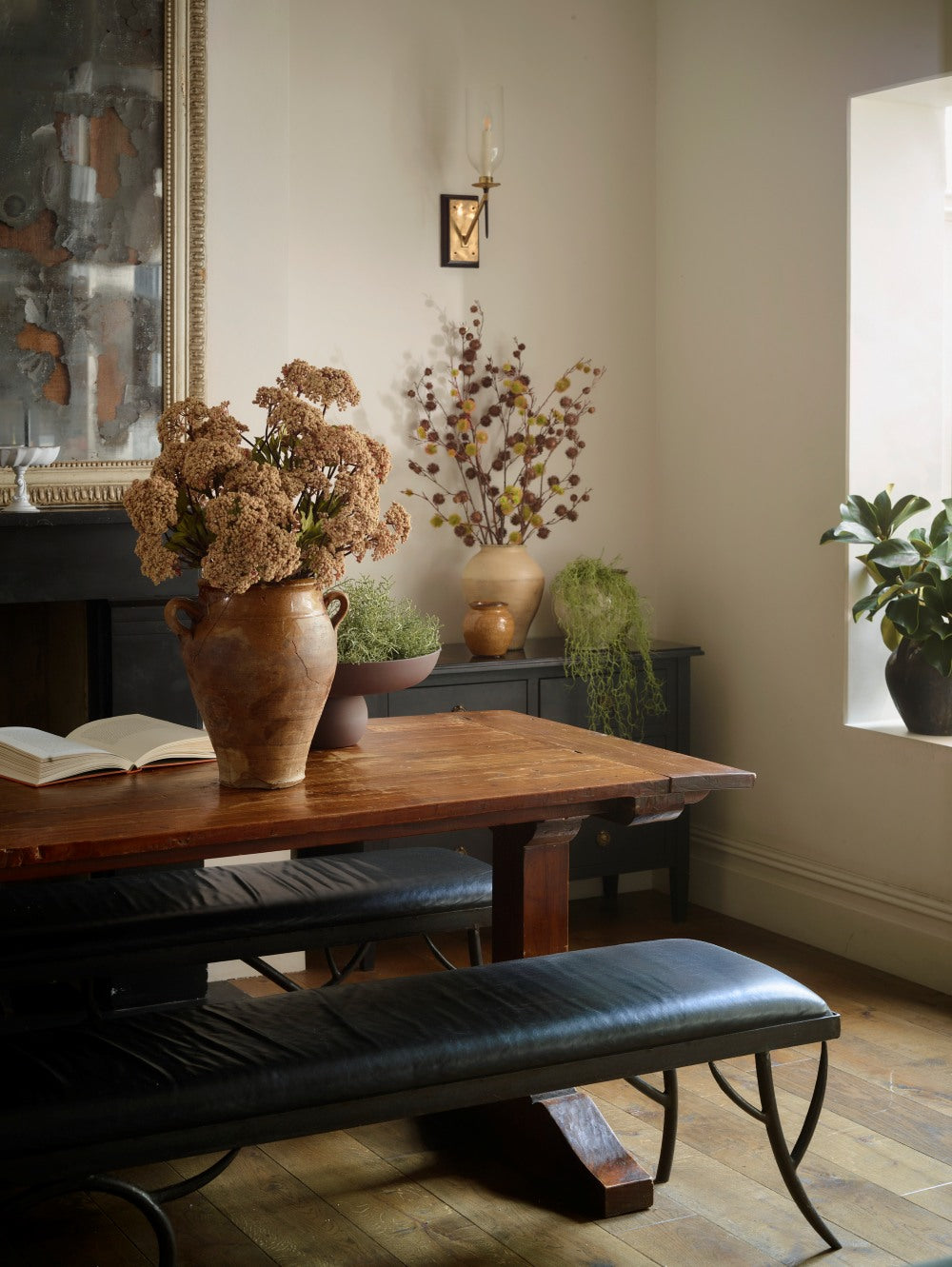 Faux stone achillea arranged in a rustic terracotta vase on a wooden dining table, with softly clustered flowers complementing a warm, traditional interior.v