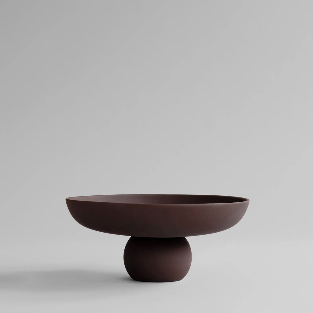 Baburu Bowl Big by 101 Copenhagen in Chocolate Brown, featuring a wide, shallow ceramic bowl balanced on a rounded pedestal base, photographed against a neutral background.
