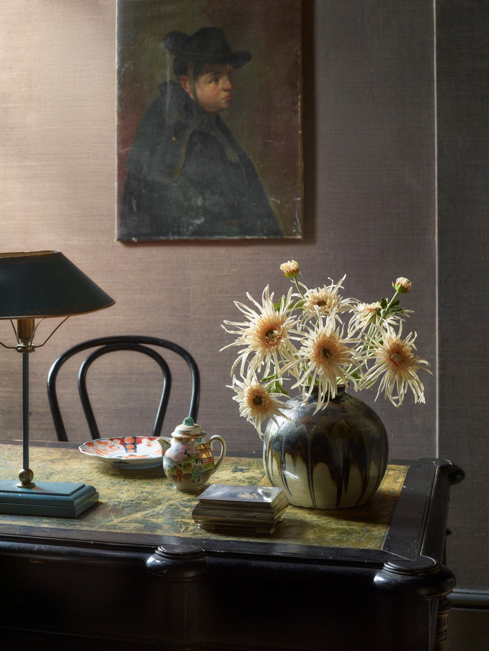 Faux Spider Chrysanthemum in Cream by Fake It Flowers, arranged in a dark ceramic vase on a wooden table in a traditional interior.