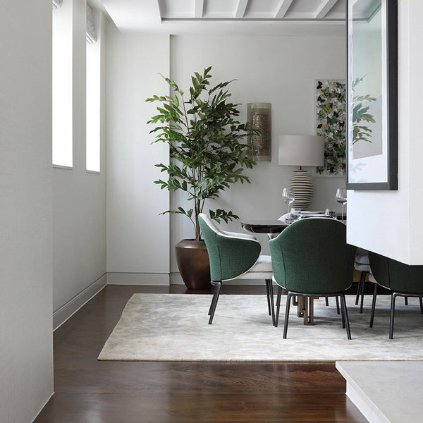 Modern interior with a staircase leading to a dining area with green chairs and a plant.
