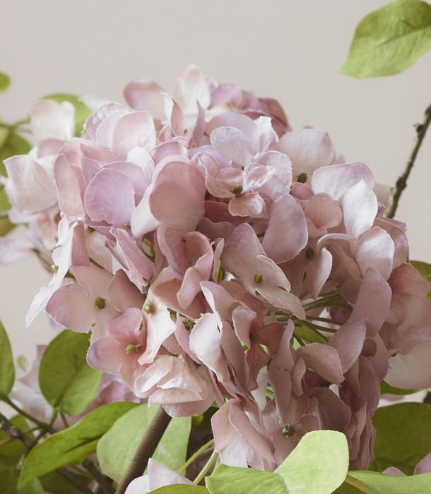 Close-up of a faux hydrangea head in dusty rose pinky mauve, delicately hand-painted leaves for natural variation with a hyper-realistic look and green leaves