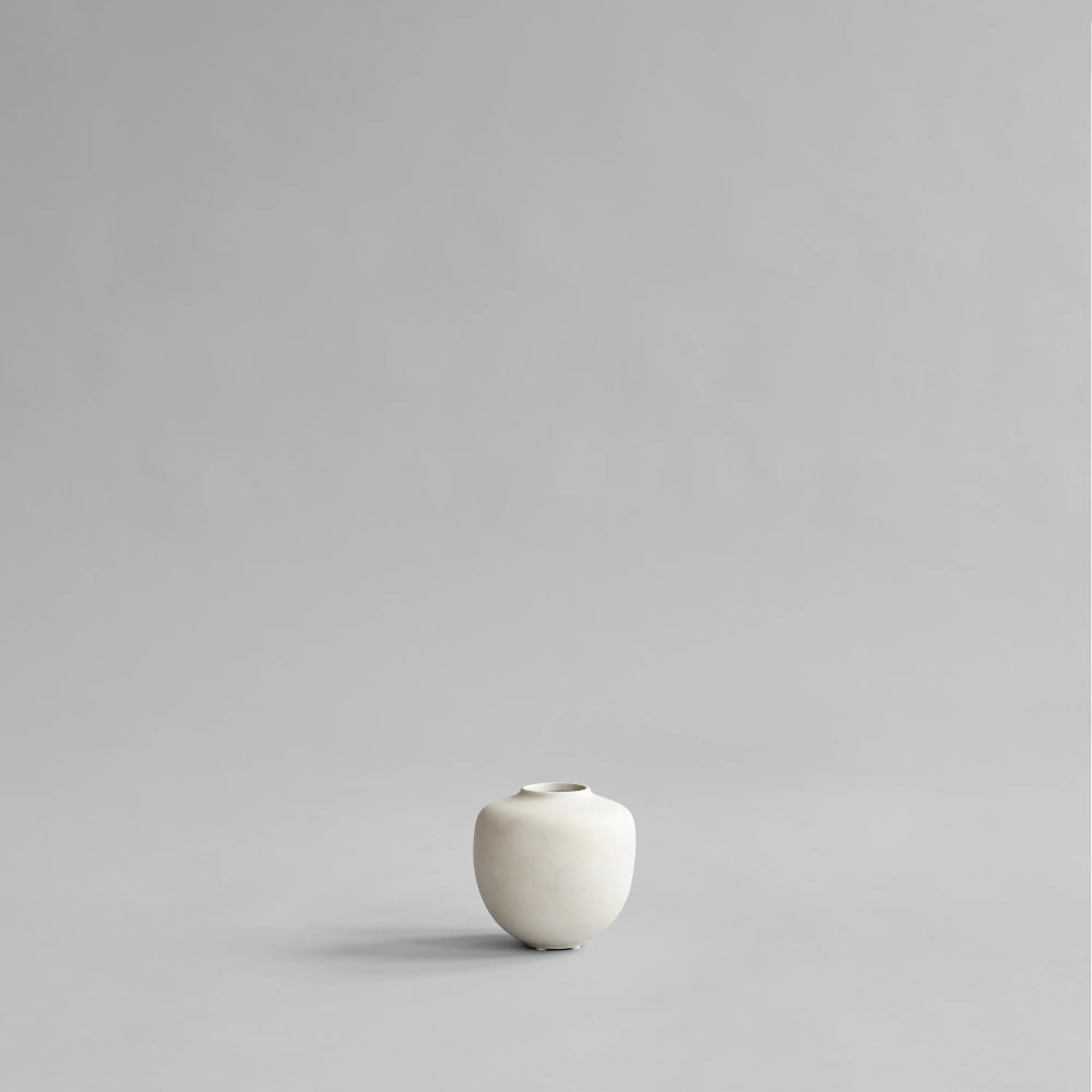 Sunao Vase Petit in Birch by 101 Copenhagen, featuring a softly rounded silhouette, narrow opening and pale cream matte ceramic finish, photographed against a light background.