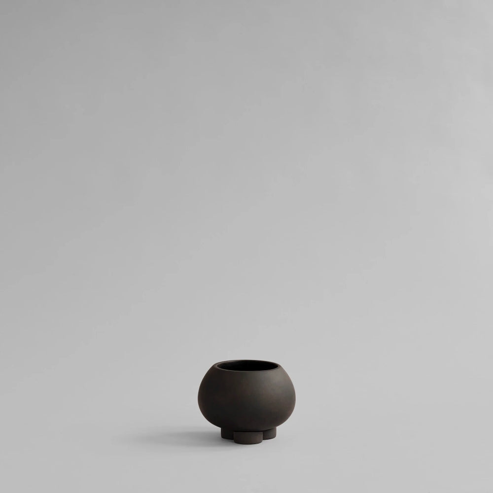 Urchin Plant Pot Petit in Coffee by 101 Copenhagen, featuring a rounded ceramic vessel with a matte dark brown finish, wide opening and three sculptural legs, photographed against a light background.